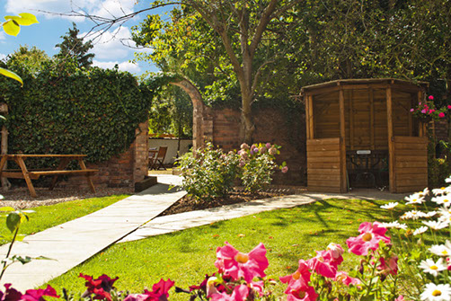 rear side path walking through garden gateway with sun shelter to the right